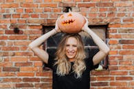 Woman in Black Sleeveless Shirt Holding Jack O Lantern