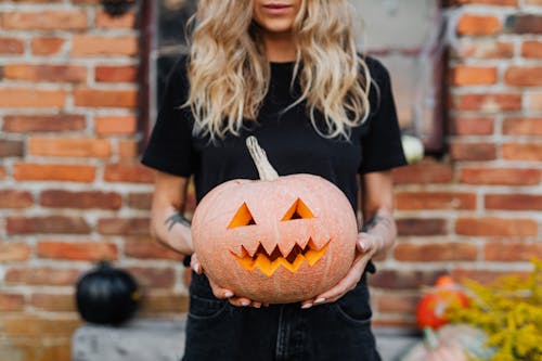 Woman Holding a Carved Pumpkin for Halloween Decoration 