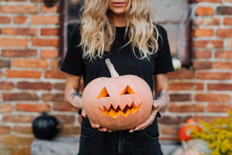 Woman Holding A Carved Pumpkin For Halloween Decoration 