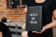 举着“不给糖就捣蛋”牌子的人的特写，非常适合万圣节主题