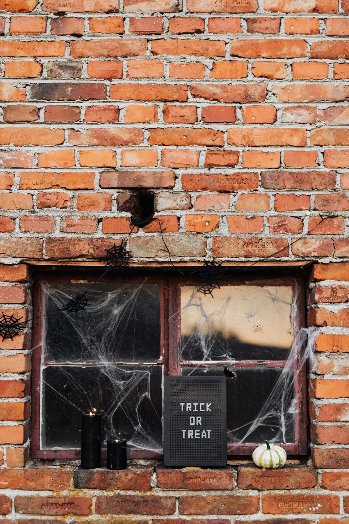 Halloween decor with cobwebs, candles and a pumpkin against a brick wall