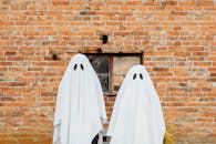 万圣节期间，两个披着白床单的幽灵站在质朴的砖墙上
