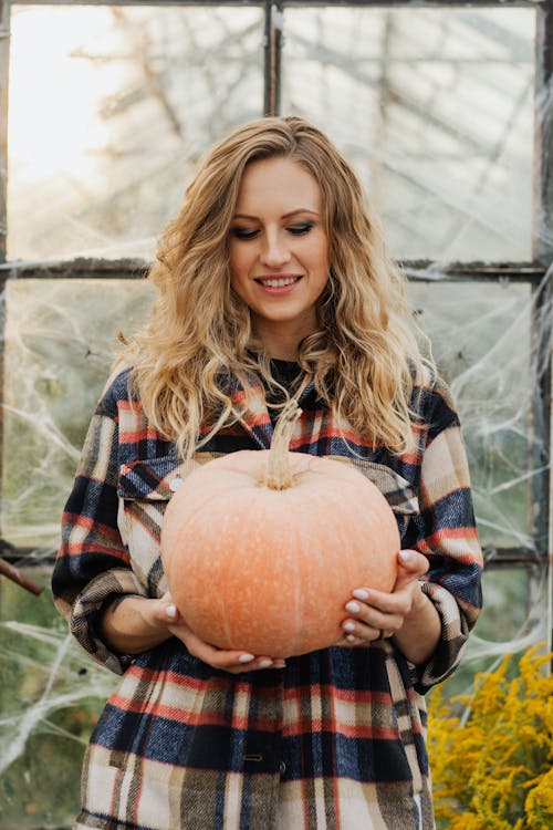 Woman Holding a Pumpkin and Smiling 