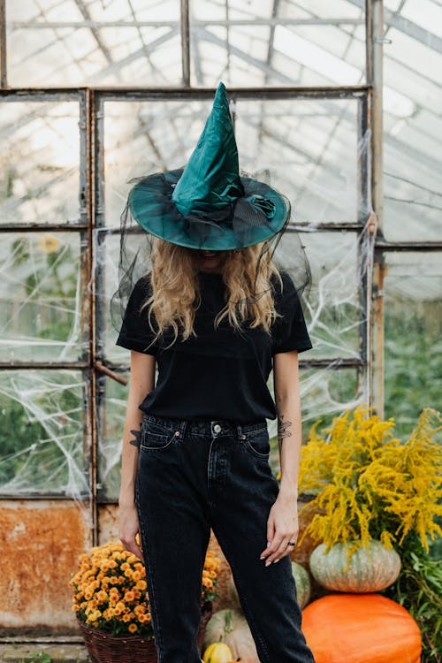 Free Woman Wearing a Witch Hat and Standing Around Pumpkins  Stock Photo