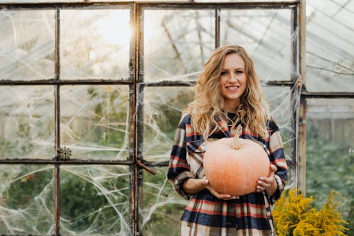 Woman Holding Pumpkin in Greenhouse