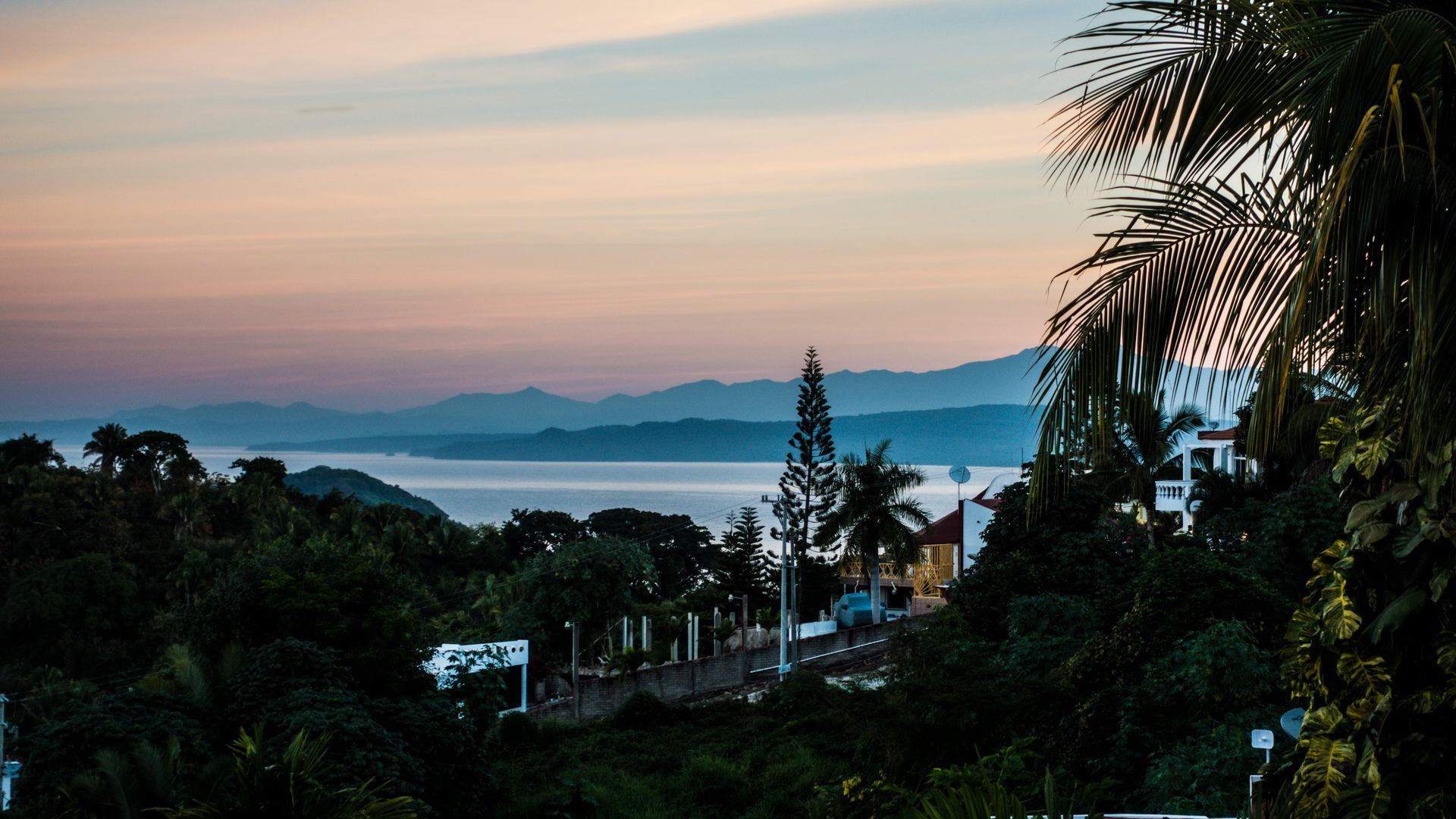 Stunning sunset over a tropical coastal landscape with ocean views and lush greenery.