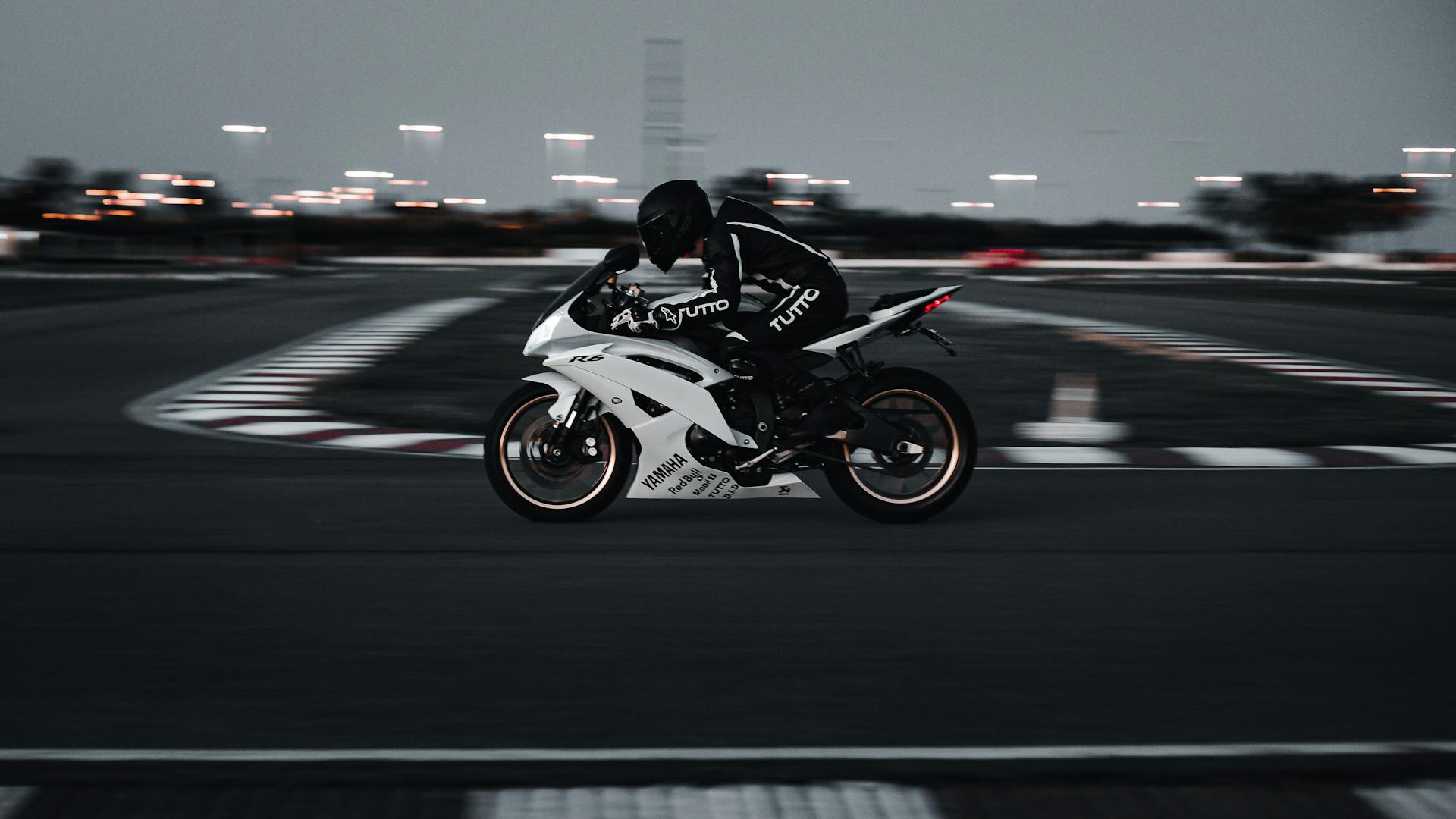 A sleek motorcycle races around a track at high speed during twilight, capturing the essence of adventure.
