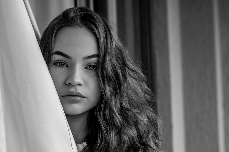 Woman Peeking Out Of Curtains