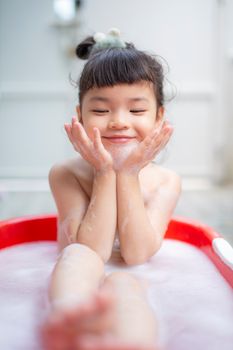 可爱的亚洲女孩在肥皂泡中享受有趣的沐浴