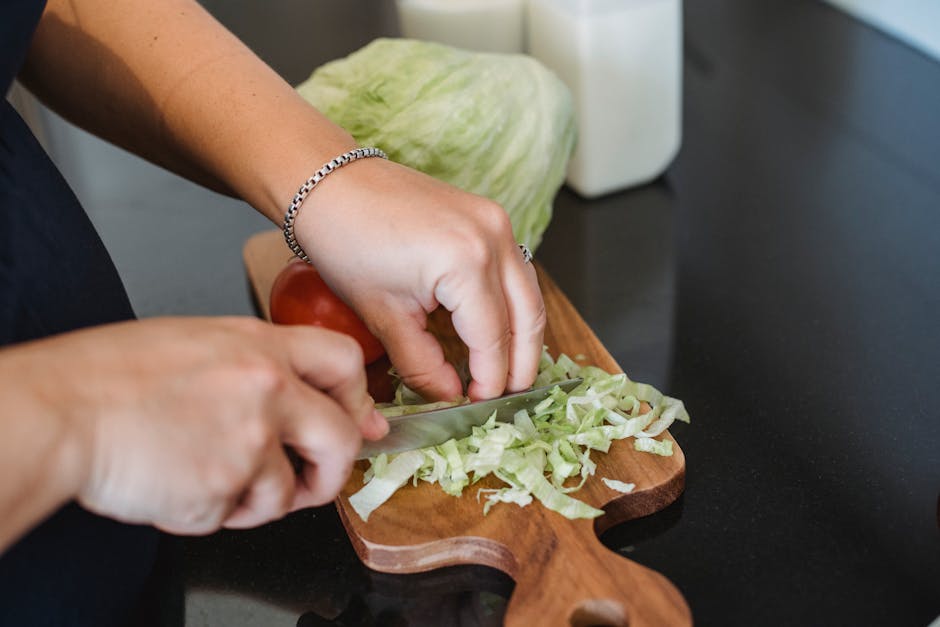 All-Clad D5 vs Tramontina: Value Showdown Close-up of a woman chopping fresh lettuce on a wooden board, perfect for healthy cooking themes.