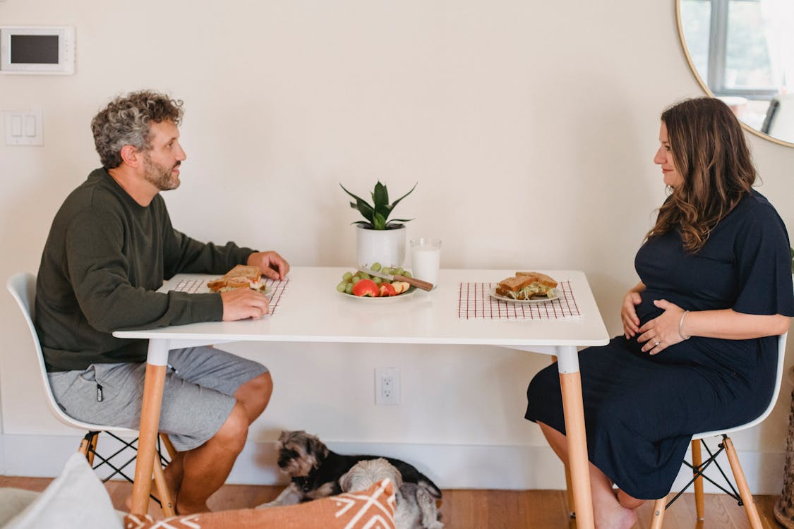 Free Happy couple eating sandwiches at breakfast in cozy apartment Stock Photo