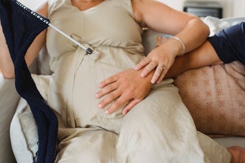 Crop pregnant woman with husband on couch