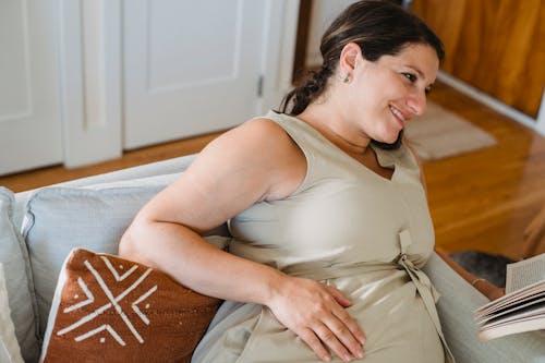 Wanita Hamil Dengan Buku Di Sofa