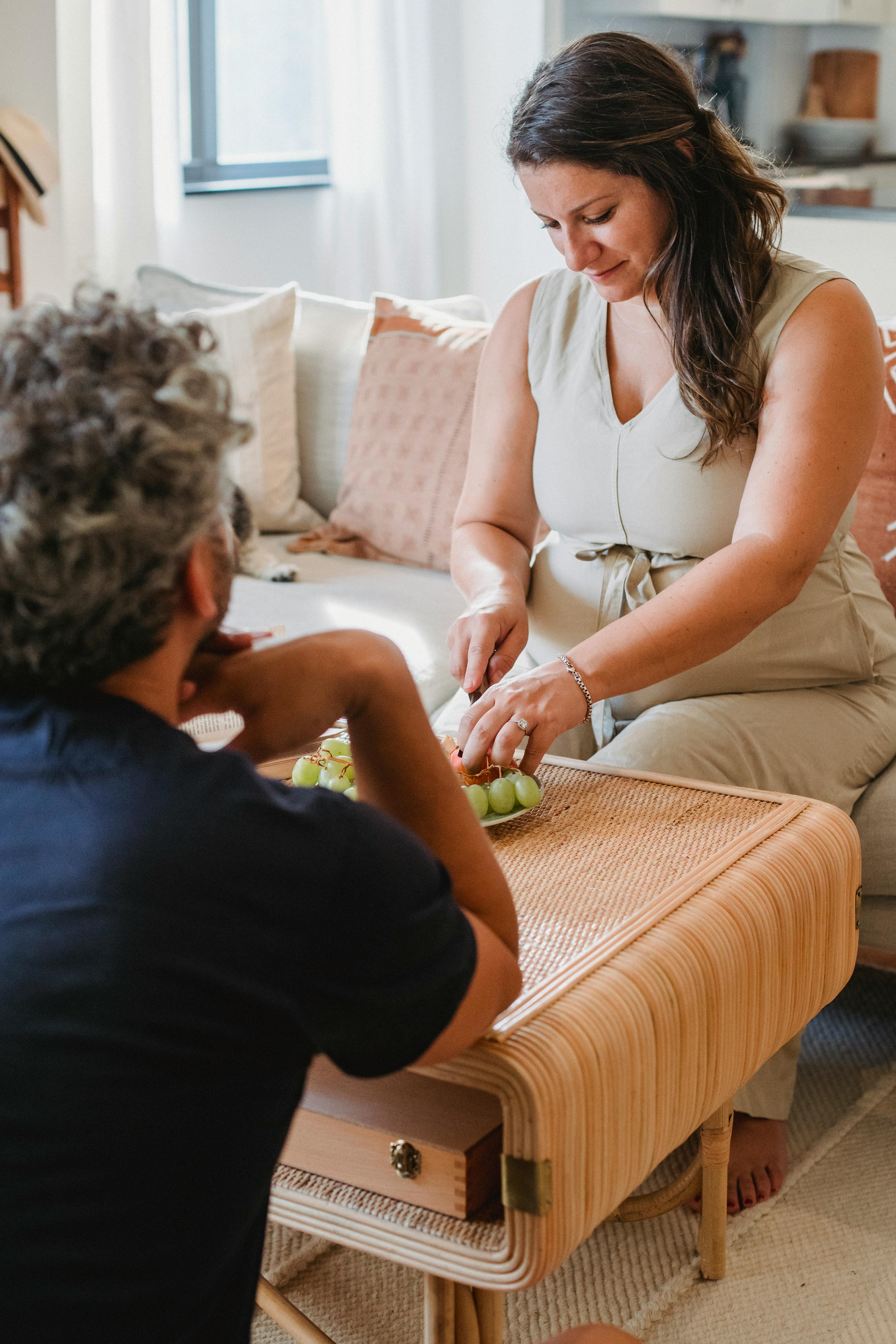 pregnant woman serving fruit chilling with man in living room