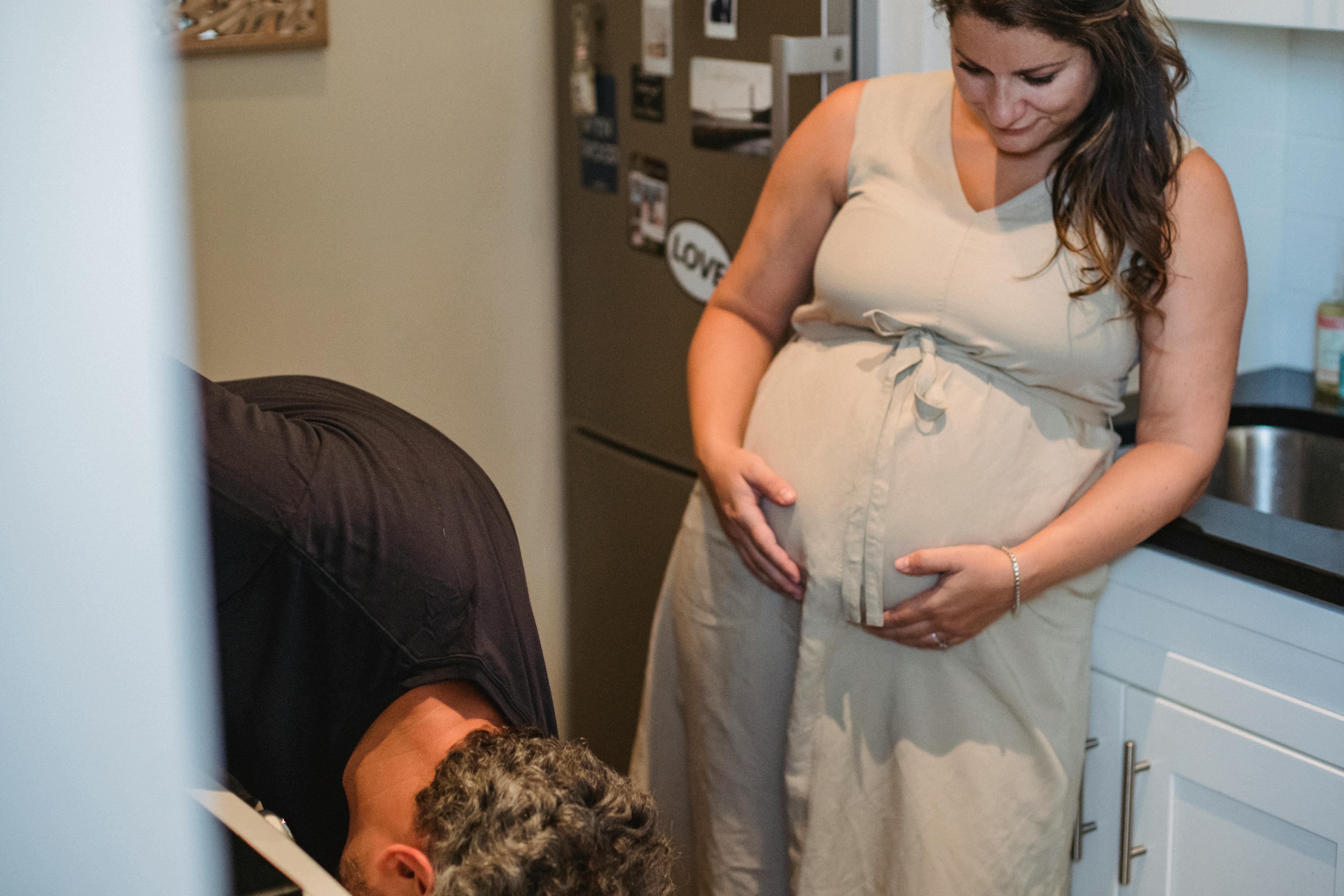 pregnant woman touching abdomen while looking at husband