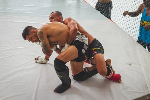 Free Two male athletes engage in intense grappling during MMA training session indoors. Stock Photo