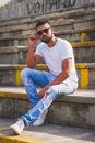 Man in White Crew Neck T-shirt and Blue Denim Jeans Sitting on Concrete Stairs