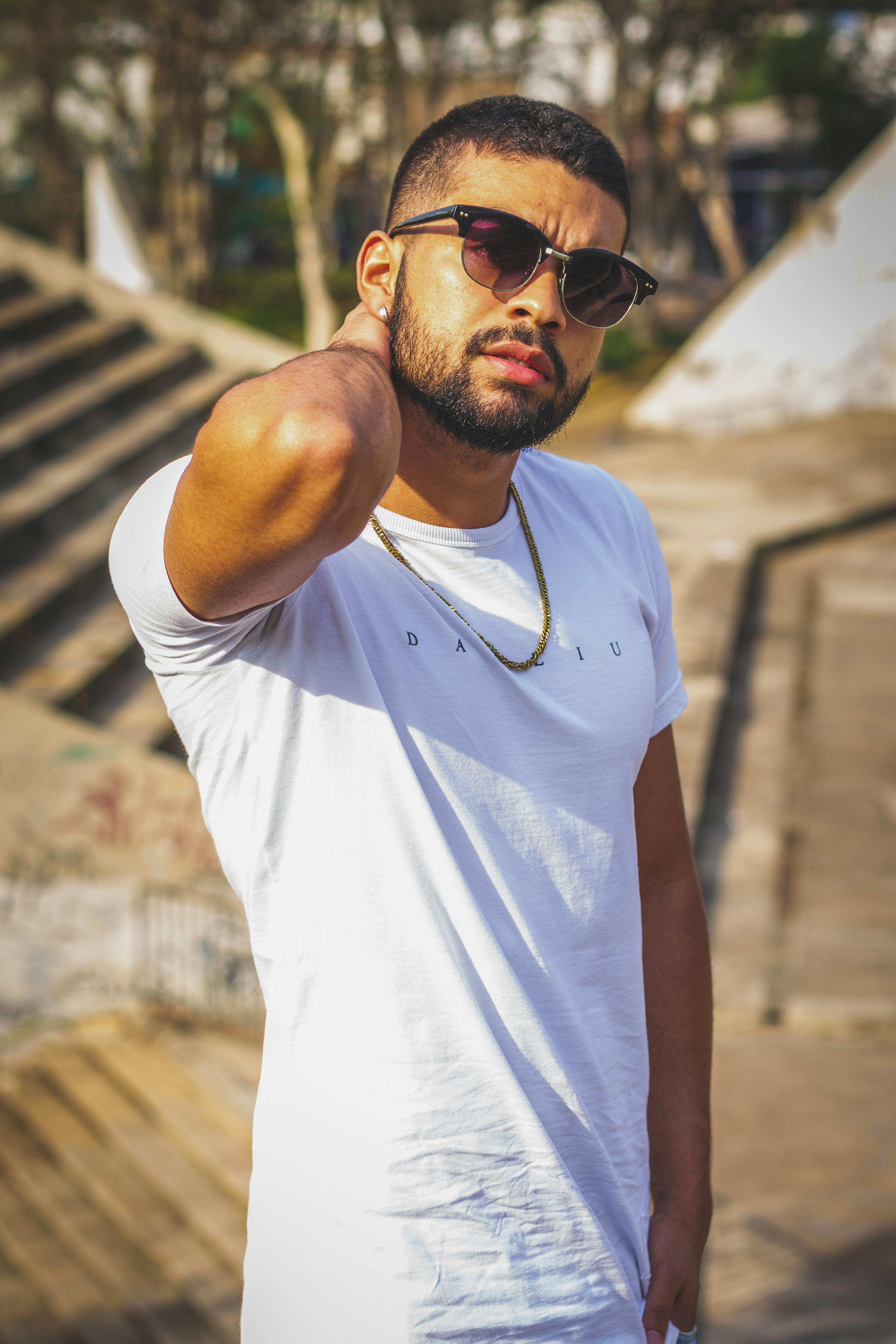Stylish young man outdoors with sunglasses in sunlight.