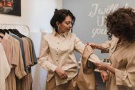 两名妇女在一家精品店购物，一起检查时尚服装中的衬衫