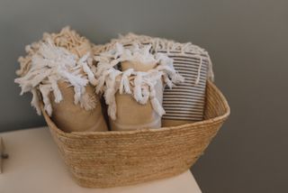 Folded linen towels stacked in a woven basket, photo by Arina Krasnikova on Pexels