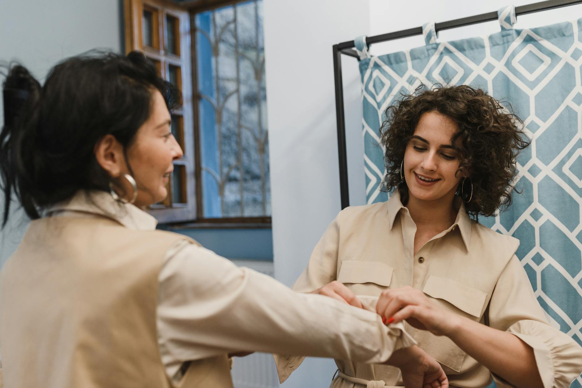 Two women enjoy a fashion fitting in a boutique, showcasing elegant style and friendly assistance.