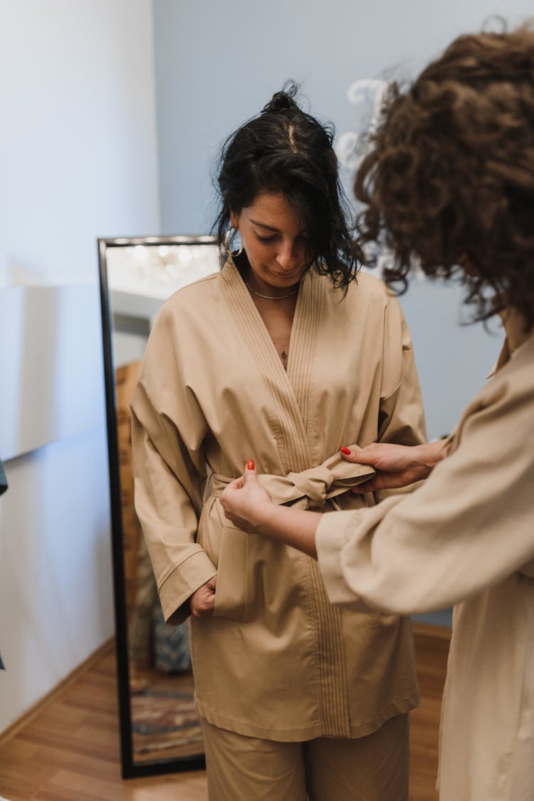 Woman Trying On Clothing With A Help Of Another Woman 