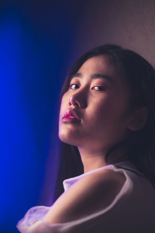 Free Artistic portrait of an Asian woman in soft, moody lighting, highlighting her contemplative expression. Stock Photo