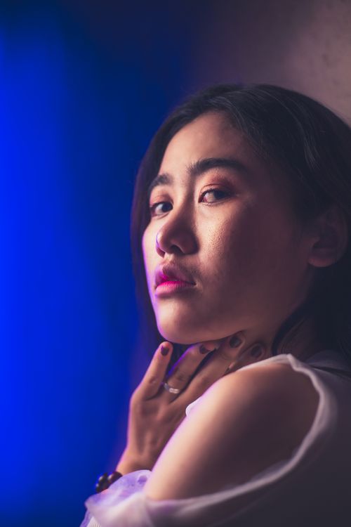 Free Elegant headshot of a woman with dramatic blue and purple lighting, showcasing her contemplative expression. Stock Photo