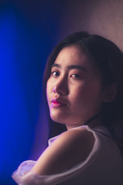 Free A captivating portrait of an Asian woman with soft lighting and a dramatic backdrop, evoking a sense of introspection. Stock Photo