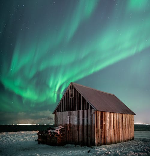 A Brown Wooden Barn Under Sky with Aurora Borealis