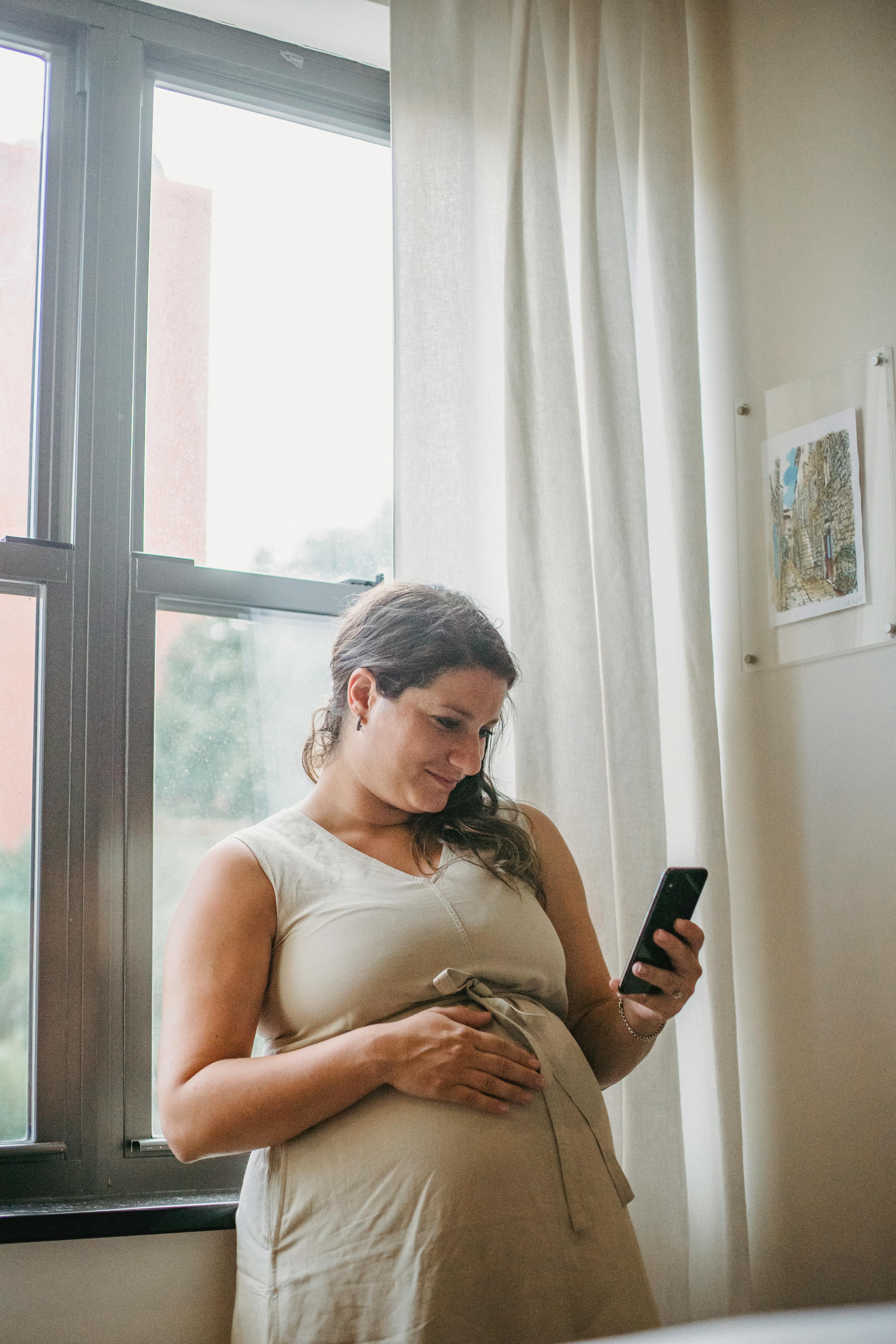 pregnant lady using phone while standing in room