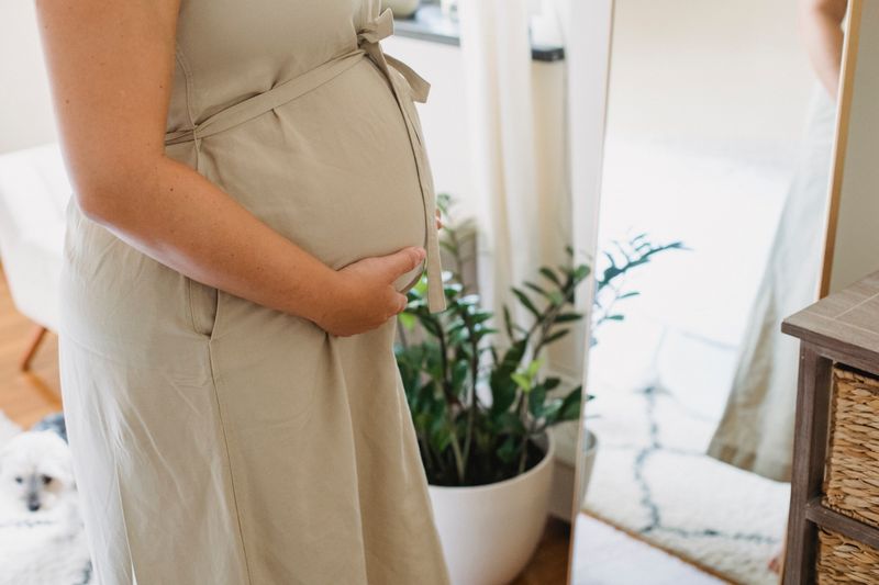 Peaceful pregnant woman at home gently holding her belly