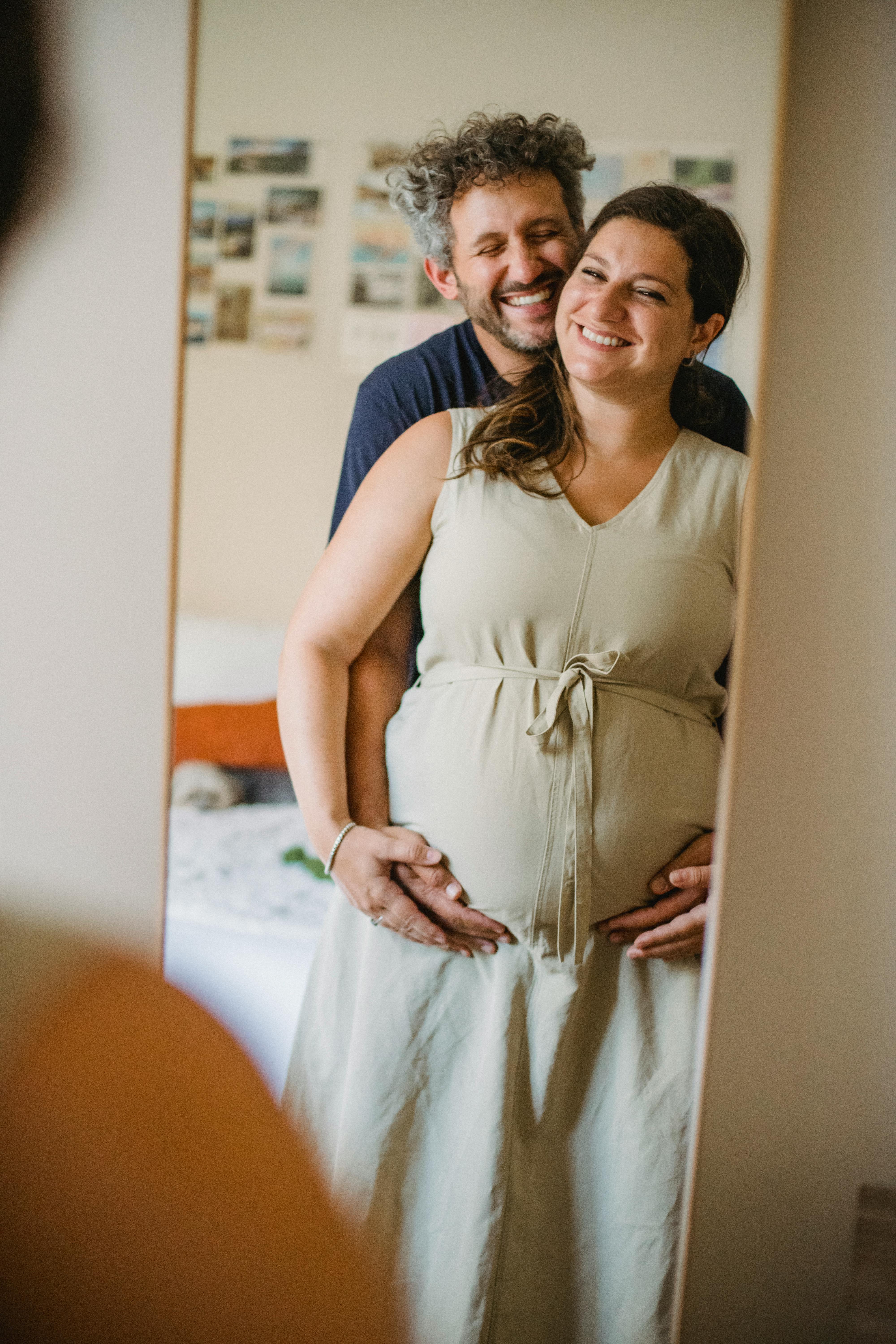 male hugging pregnant female at home