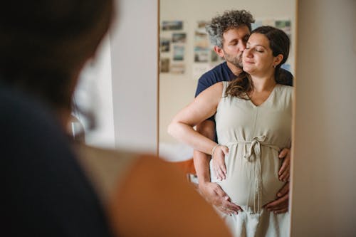 Man hugging pregnant woman belly in room