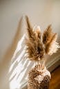 High angle of wicker vase with dried brown plants on floor in room