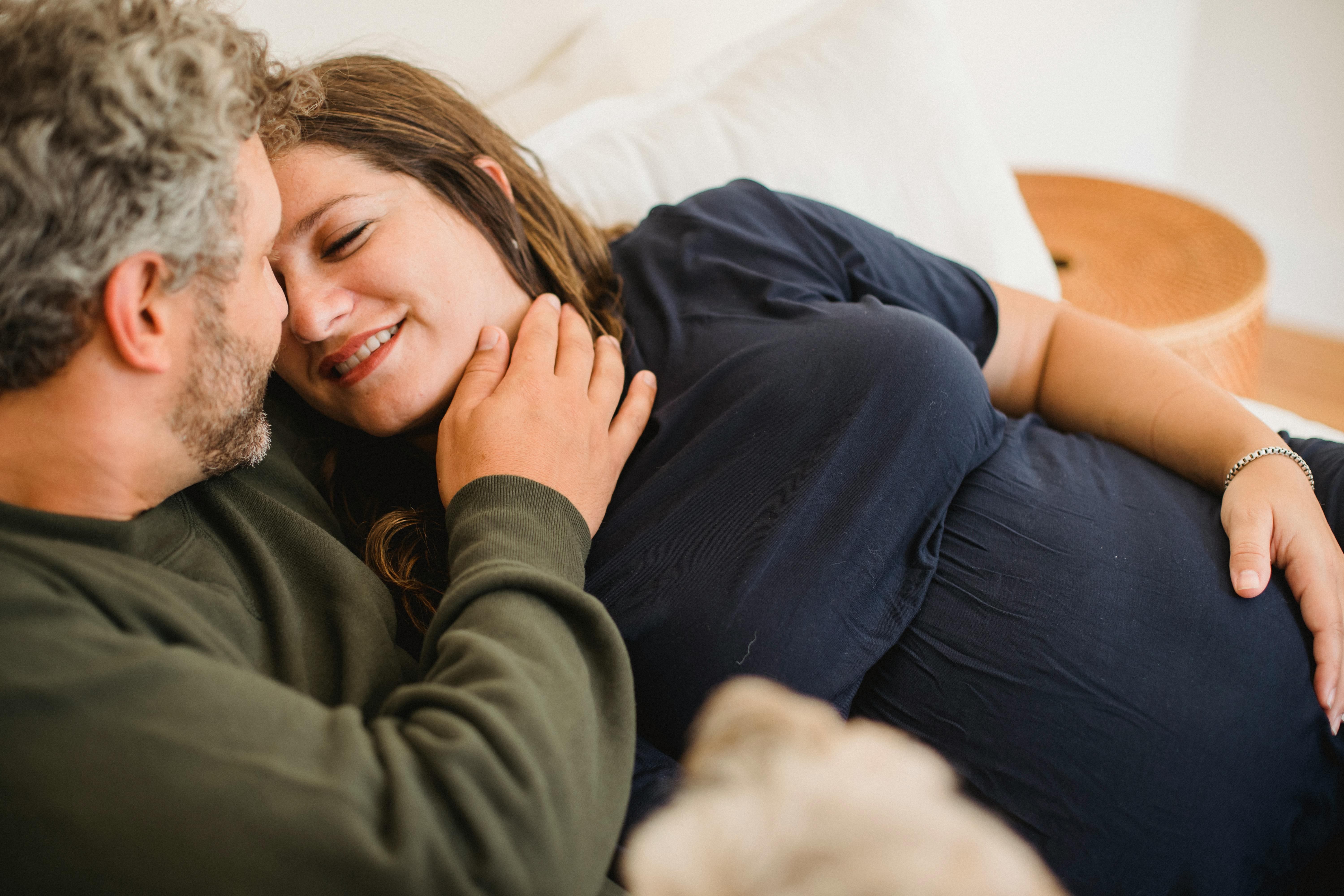 crop man stroking pregnant wife on bed in house