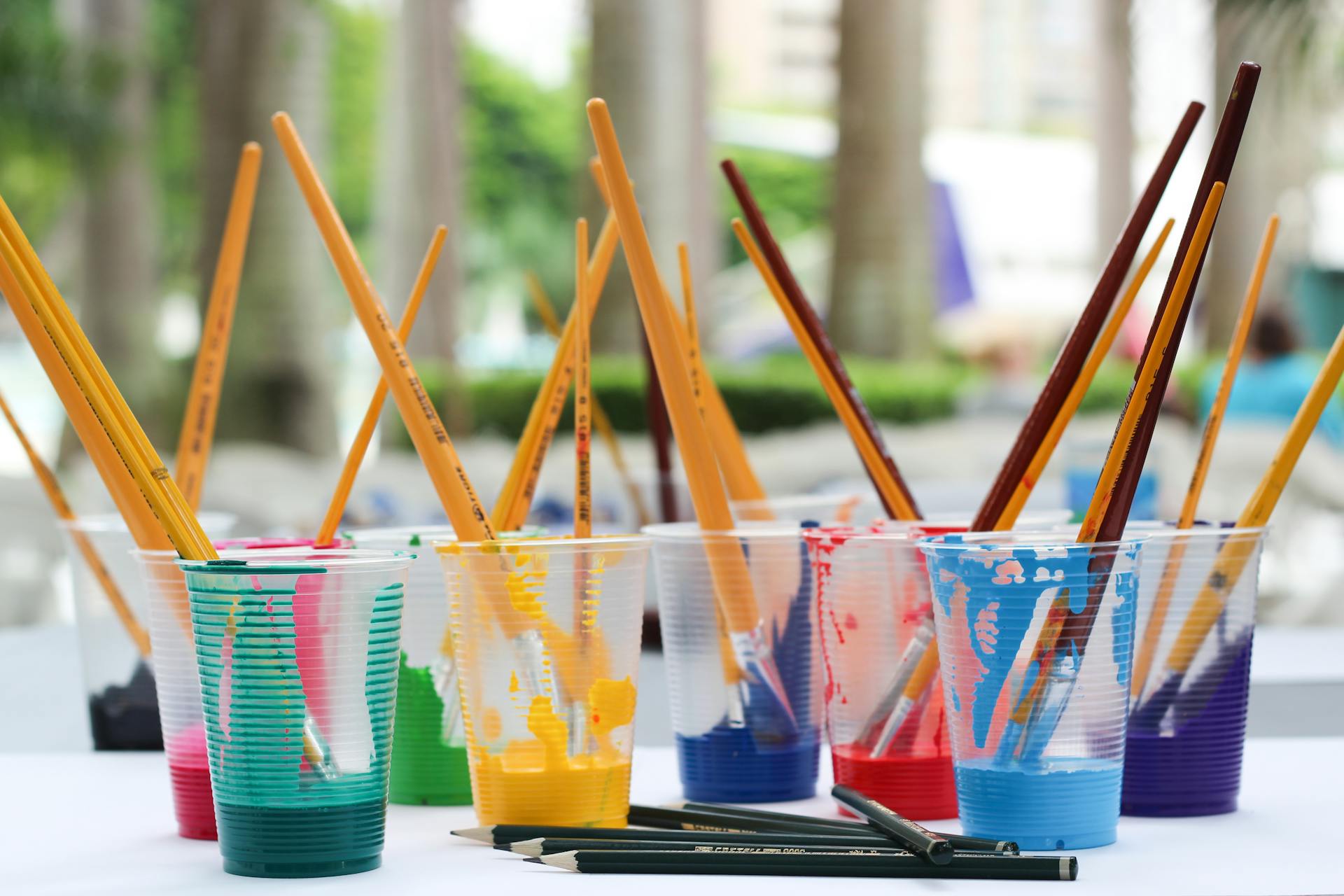 Vibrant paint brushes and pencils in plastic cups for arts and crafts