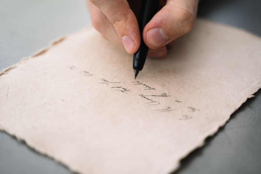Close-up of a hand writing with a pen on textured paper