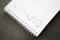 A close-up of a spiral notebook with an inspirational quote written in calligraphy on a blank page.