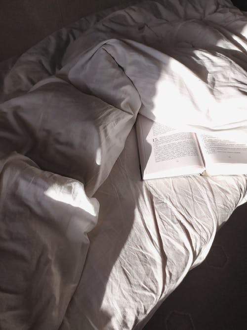 Bed with disheveled sheets and opened book