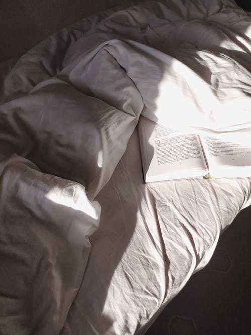 Opened book placed on soft bed · Free Stock Photo