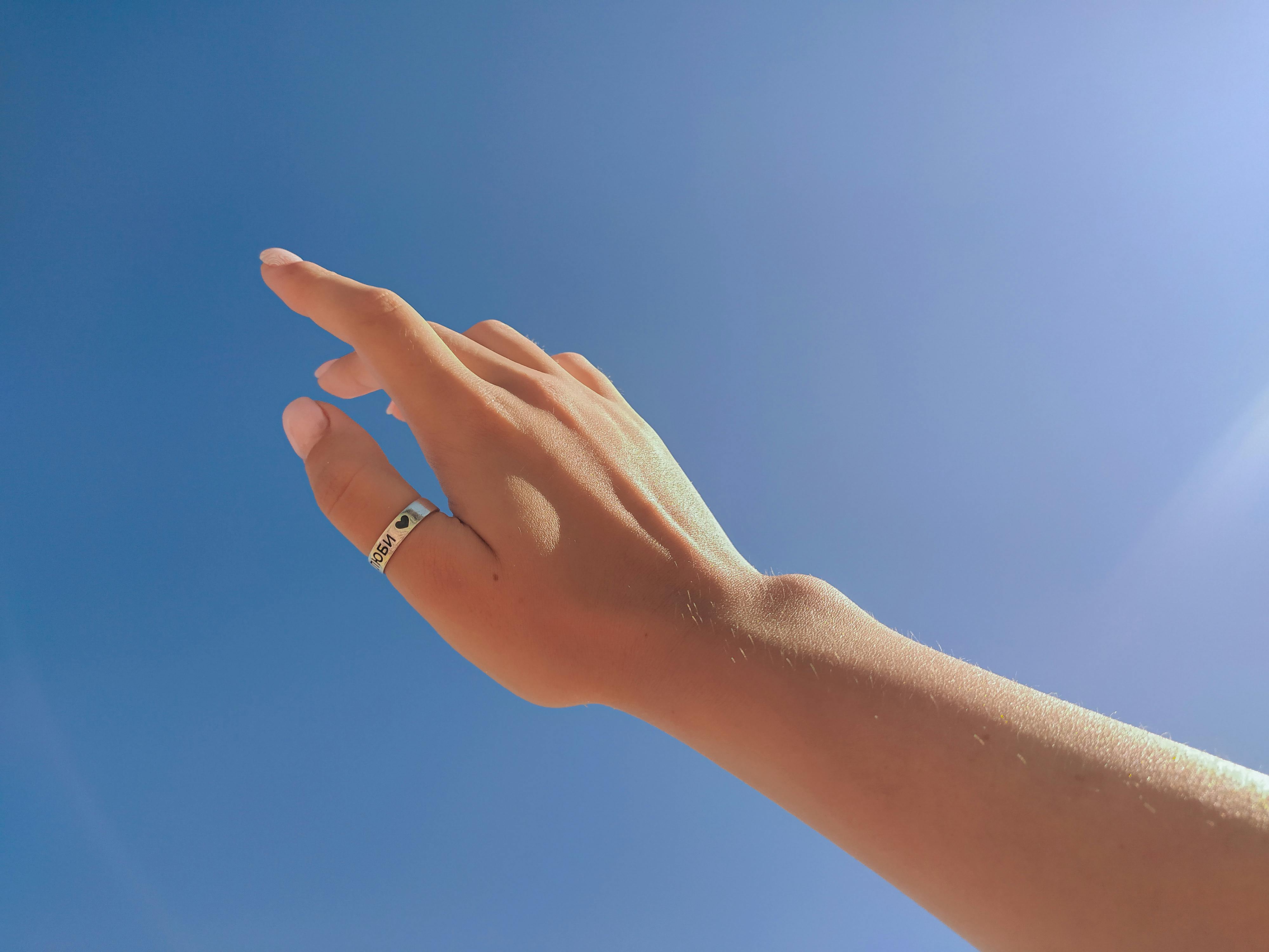 Crop faceless female hand against blue sky · Free Stock Photo