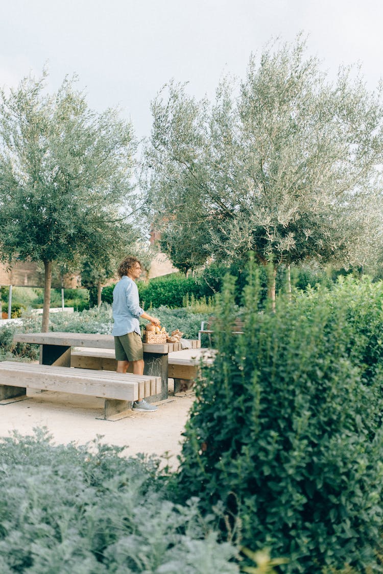 Man Standing Beside A Table On A Garden