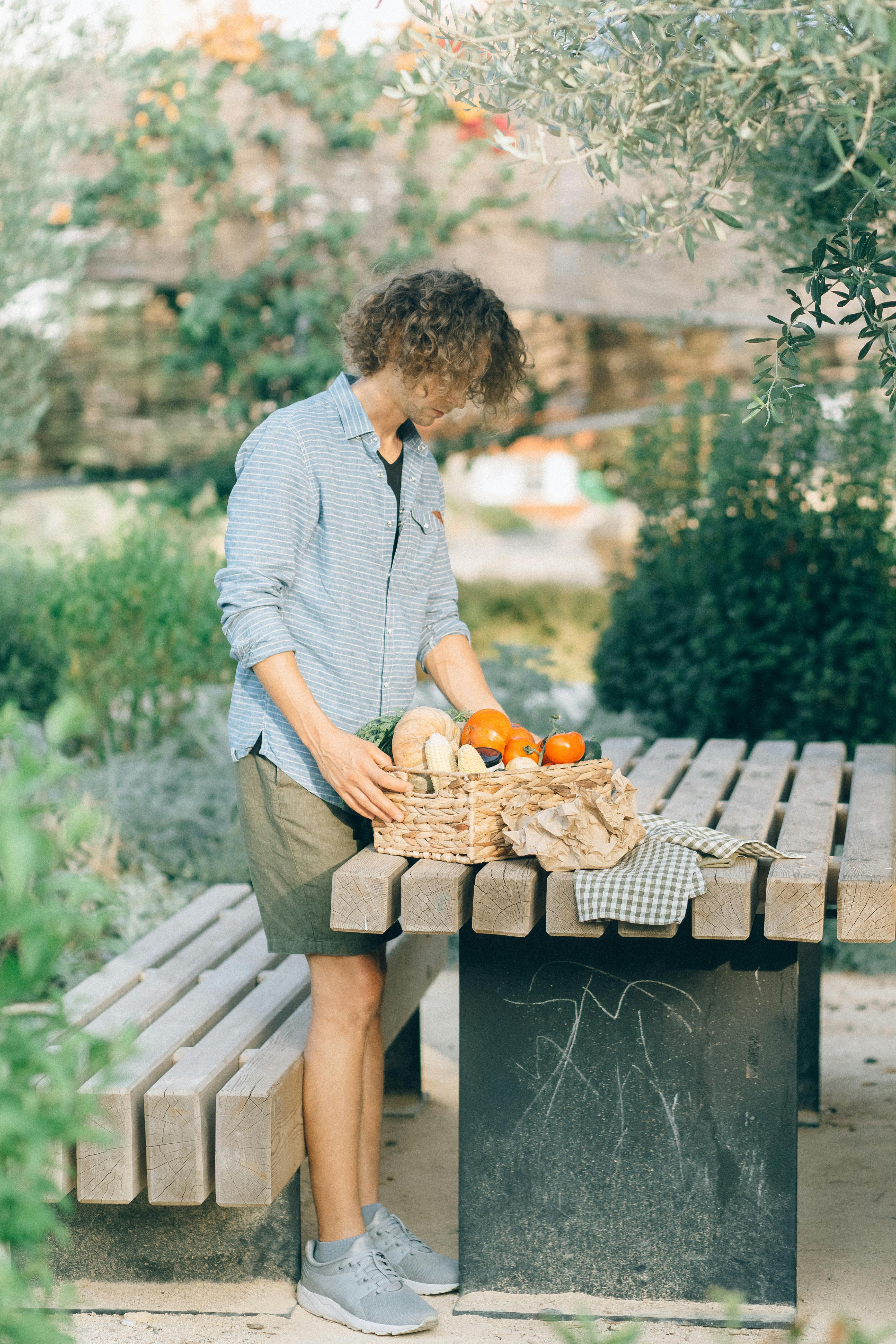 man in blue dress shirt sitting on brown wooden bench