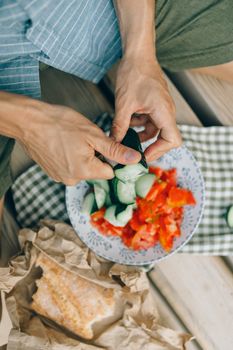 Close-up of hands slicing cucumbers and tomatoes for a healthy salad, indoors.