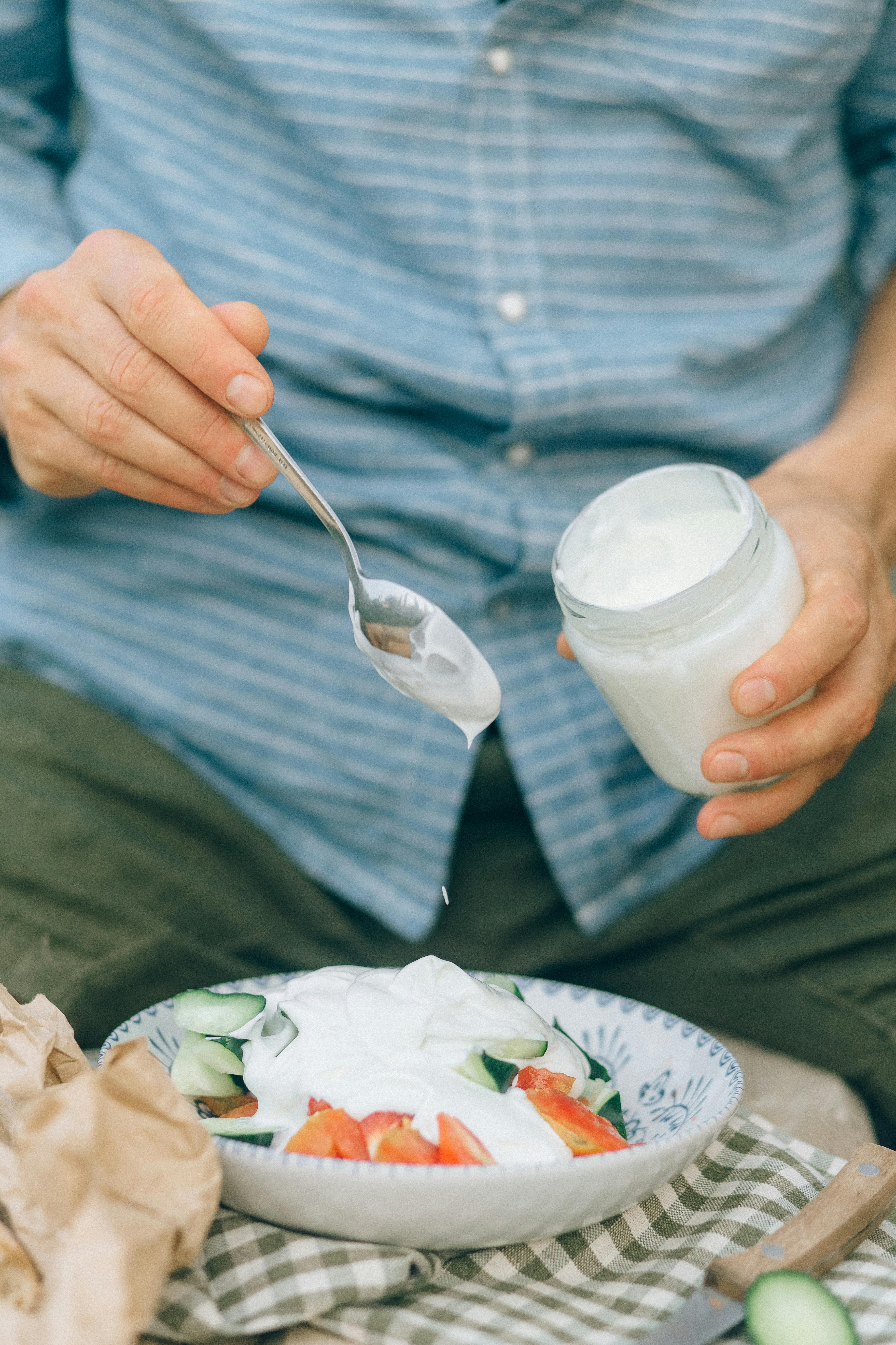 person holding silver spoon and white plastic cup