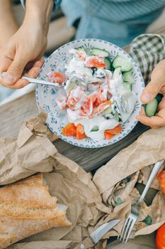 A vibrant summer salad with fresh vegetables and bread on a rustic table.