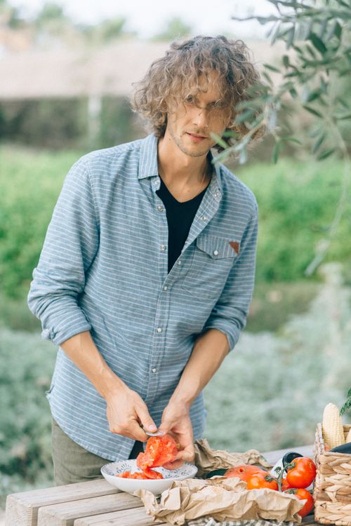 Free A man slicing tomatoes in a garden setup, capturing lifestyle and organic food preparation. Stock Photo