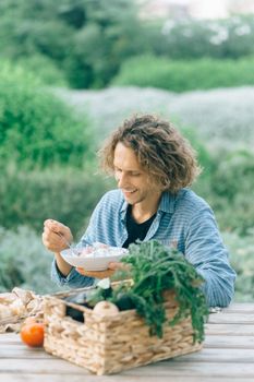 Happy man eating a fresh, organic salad outdoors. Enjoying a healthy lifestyle surrounded by nature.