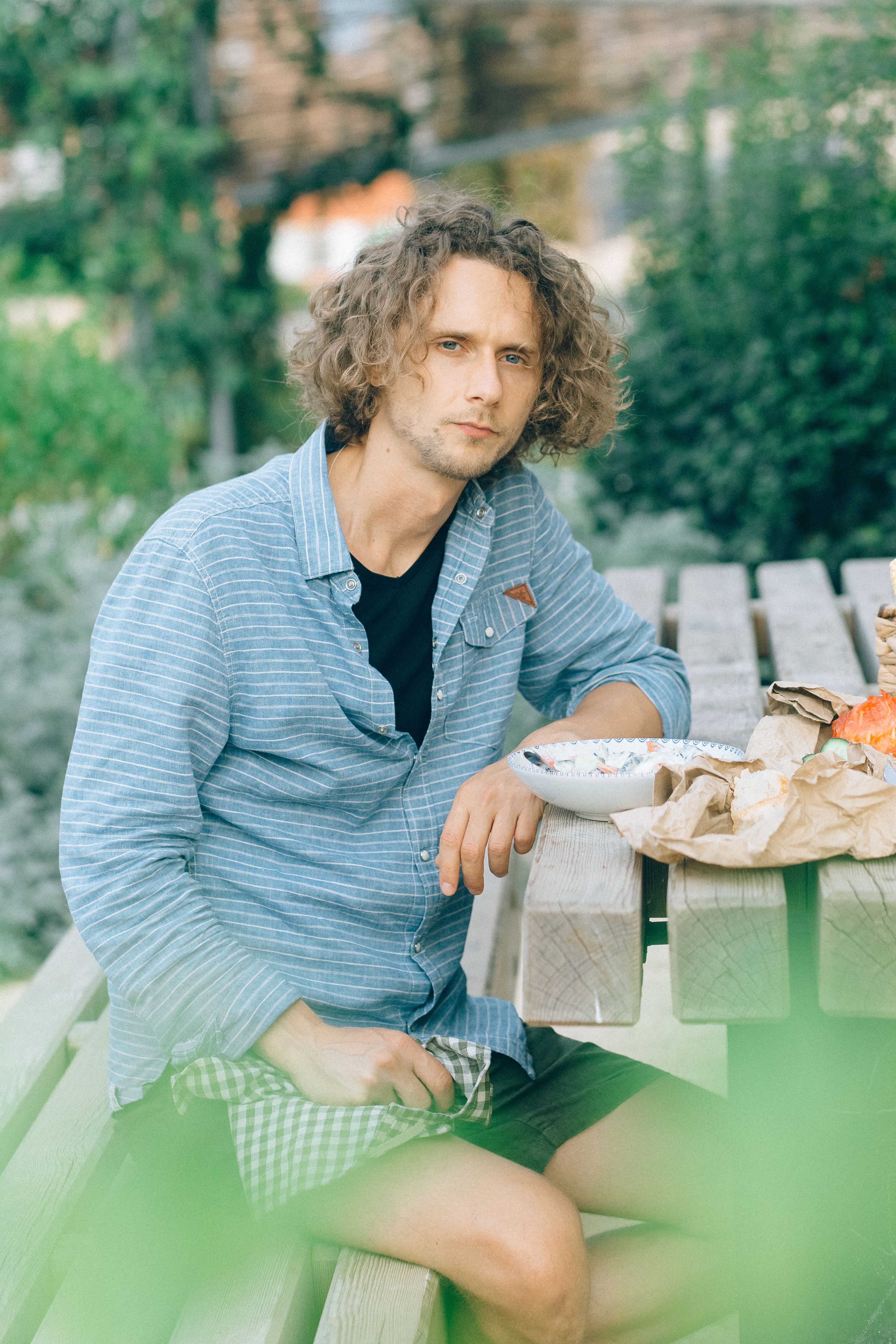 Man sitting at a picnic table with a salad bowl, enjoying a relaxing moment outdoors.